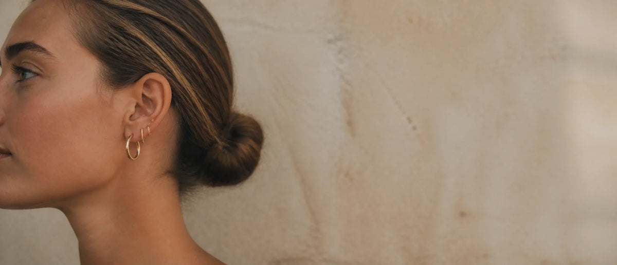 Stacked gold MAREA hoops on a second-piercing ear