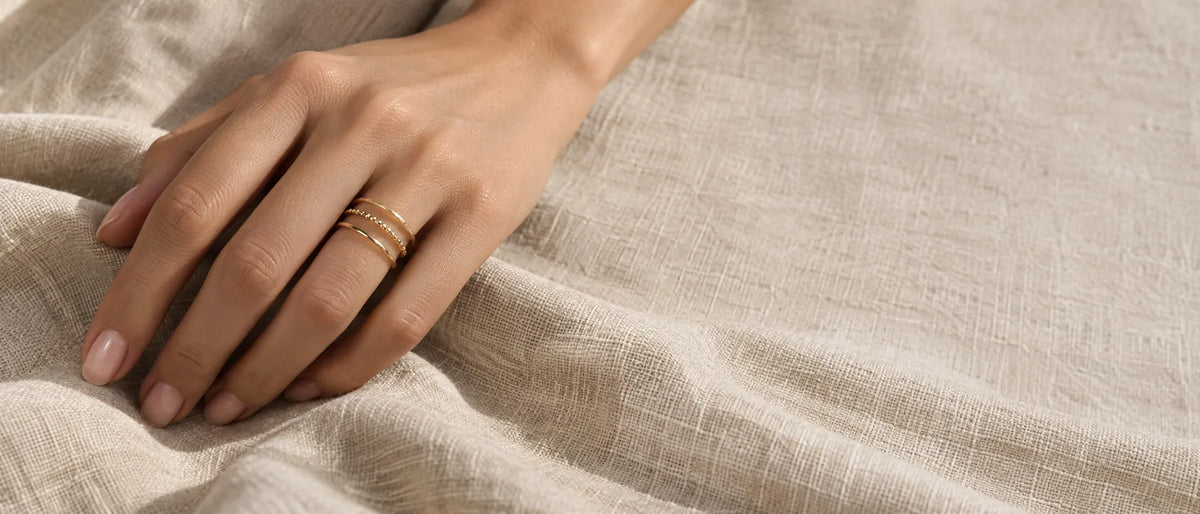 Three stacked delicate gold MARÉA rings on a hand