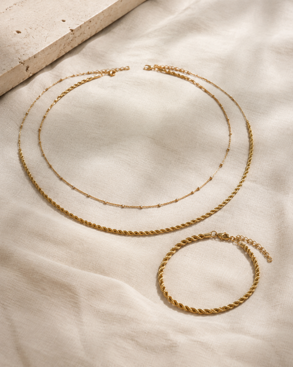 The No-React Set in gold — beaded choker, rope chain and matching rope bracelet on linen