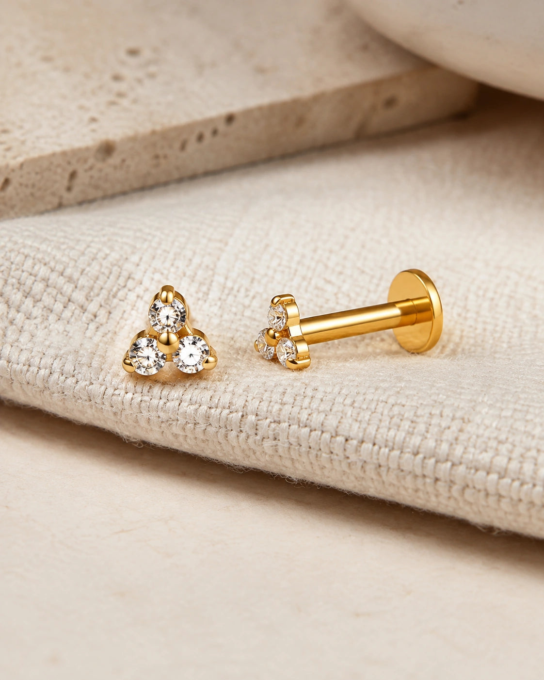 Gold trinity CZ titanium flatback stud earrings by MAREA on natural linen