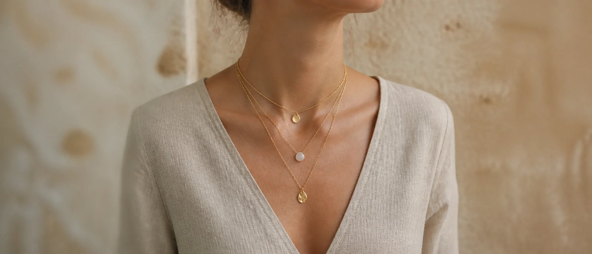 Layered gold MAREA necklaces worn on the collarbone