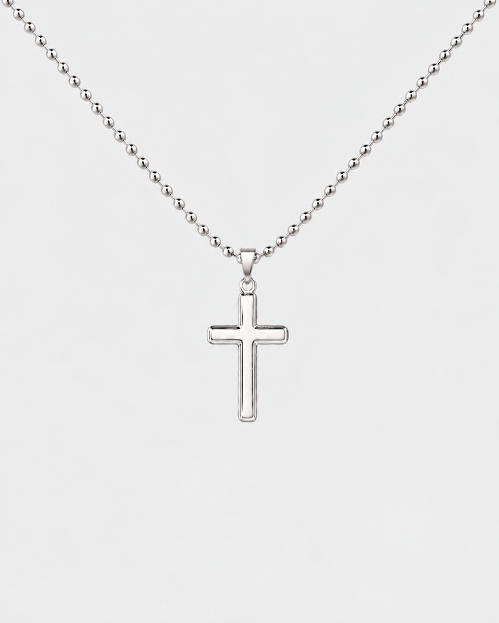 Cross necklace in silver-tone stainless steel on a light grey background