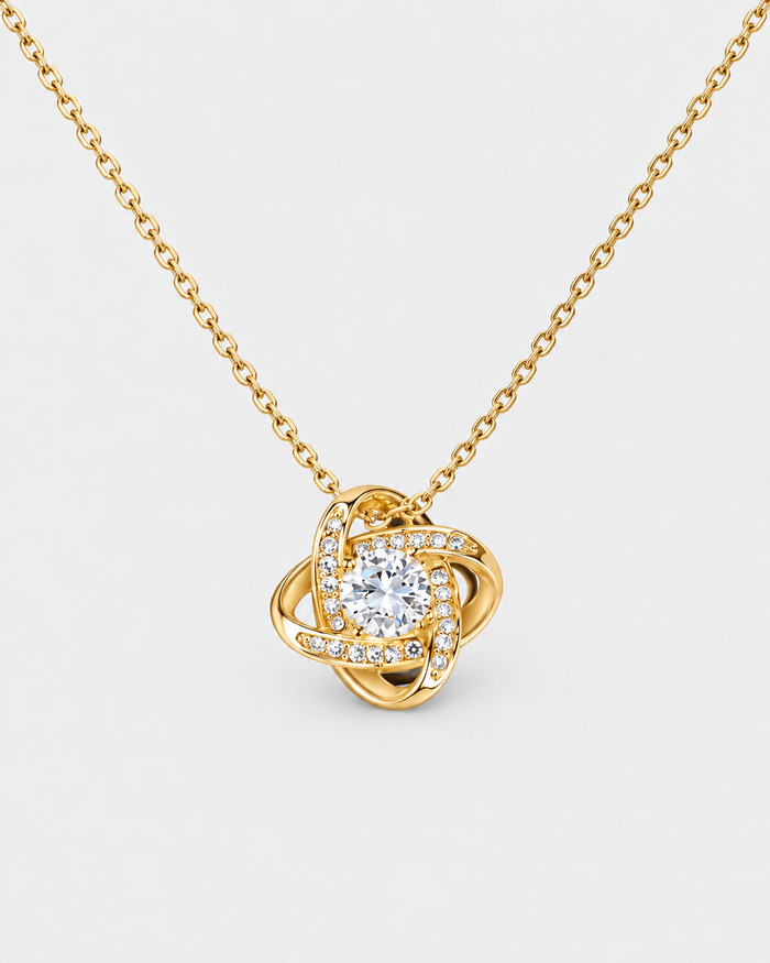 Love Knot necklace in gold-tone stainless steel on a light grey background