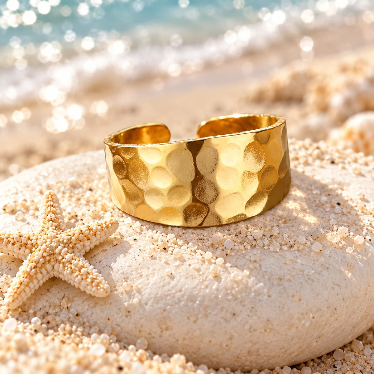 MARÉA Hammered Band wide gold open ring with hammered texture on a white stone with a starfish