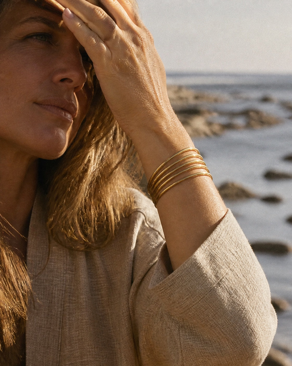 Woman with arm raised, the gold MAREA Cove Stack sliding down her forearm