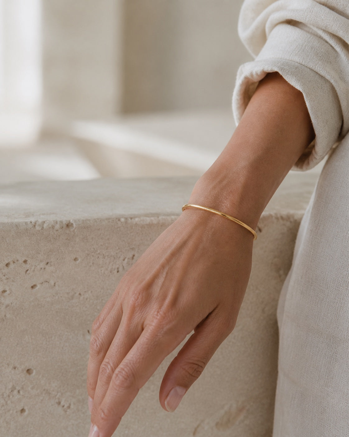 Woman wearing the thin gold MAREA Shoreline Bangle on her wrist