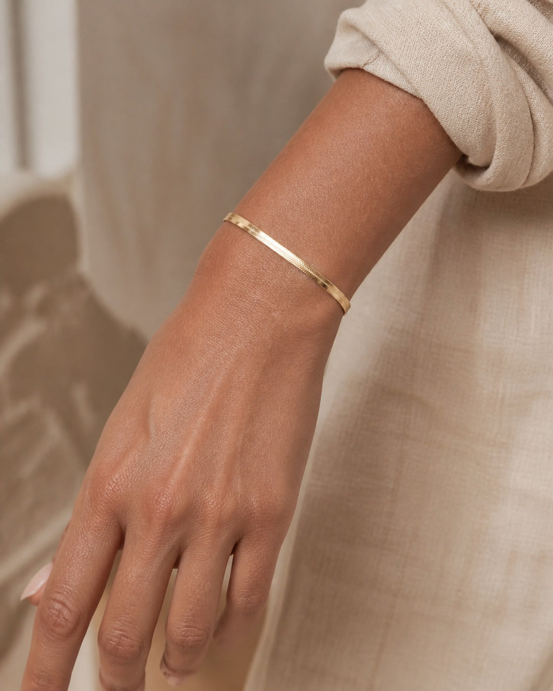 Woman wearing the gold MAREA Herringbone Bracelet on her wrist