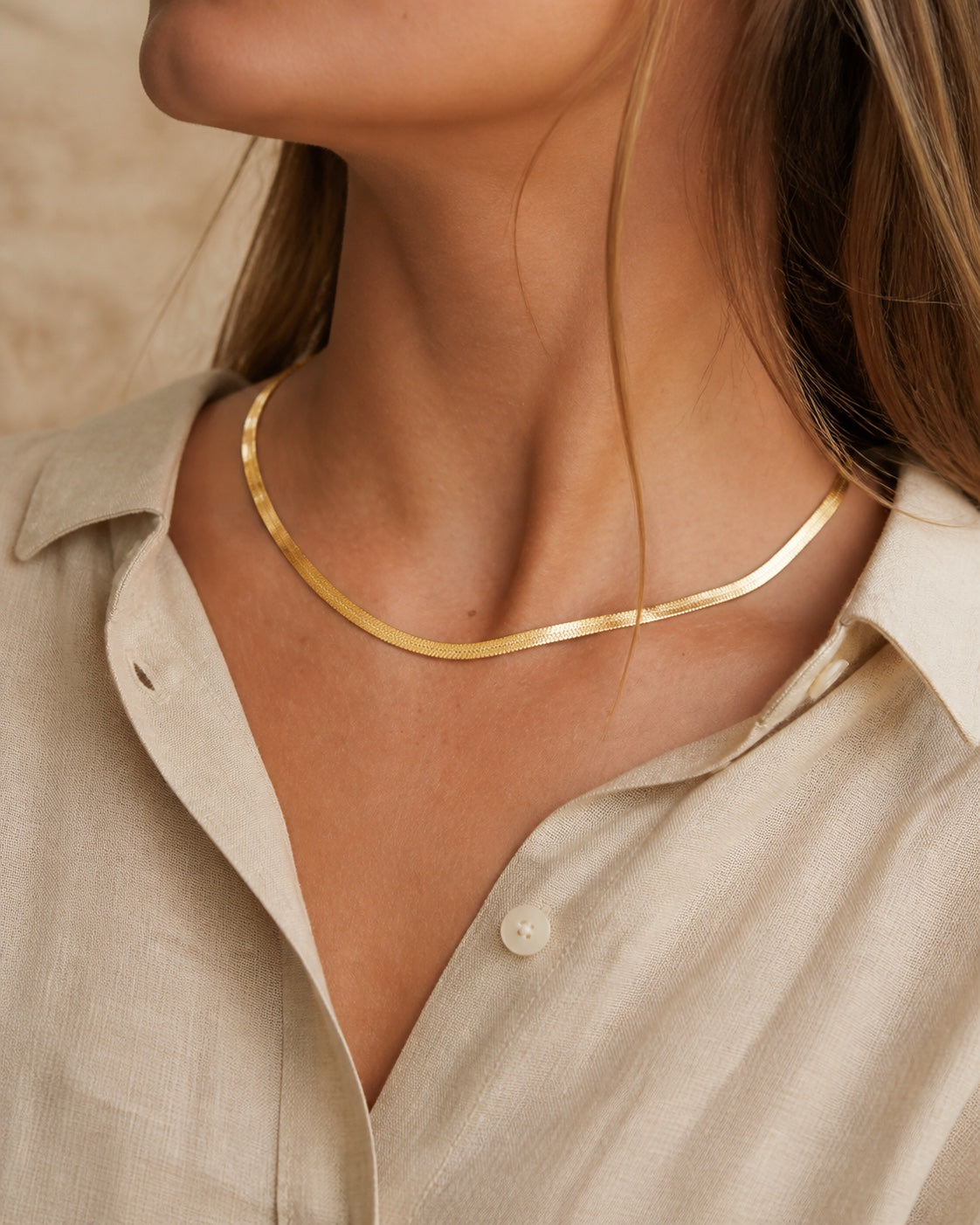 Woman wearing the gold MAREA Herringbone Necklace flat at the throat