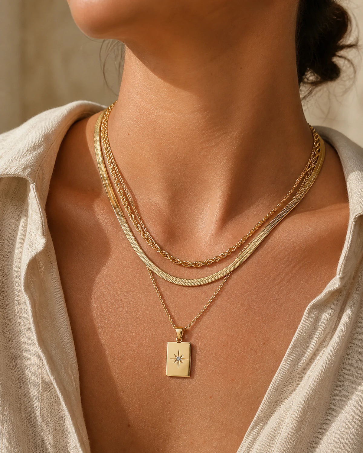 Woman wearing the gold MAREA North Star Set, three layered chains at the collarbone
