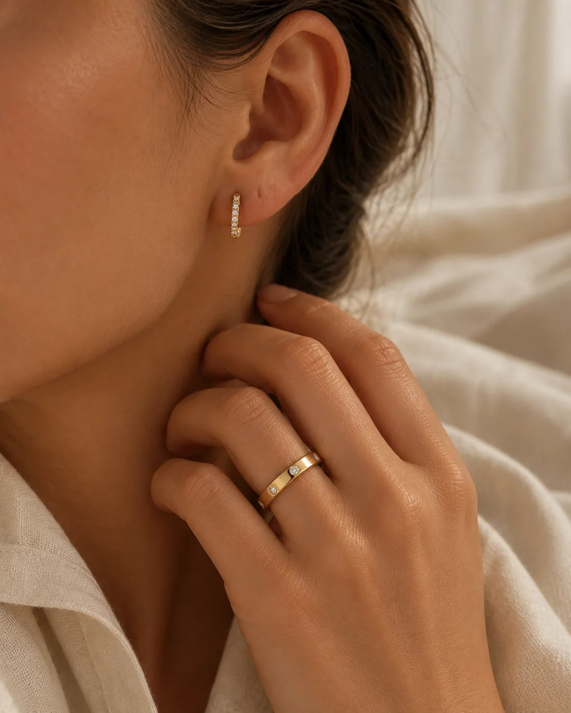 Woman wearing the MARÉA pavé huggie in her ear and the pavé ring on her hand